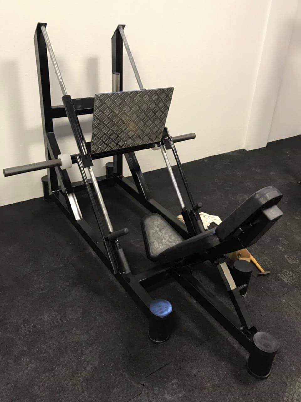 Leg press sprava sa kosim vođicama, rifljanom pločom za stopala i naslonom sa jastucima, crna izvedba